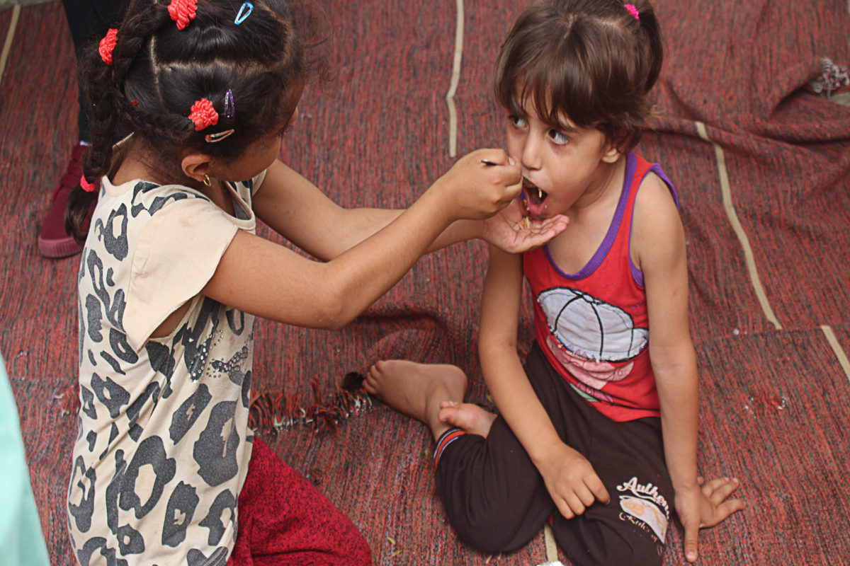 Girls sharing a hot meal on the floor of their house in Gaza.