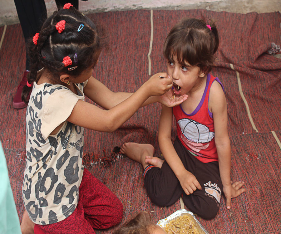 Girls sharing a hot meal on the floor of their house in Gaza.