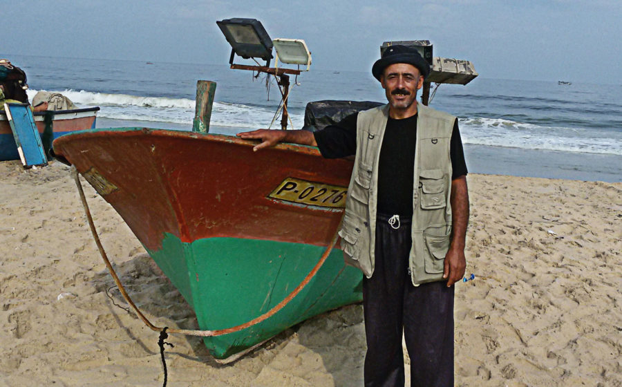 Adel Ferwana stands near his fishing boat in Gaza.