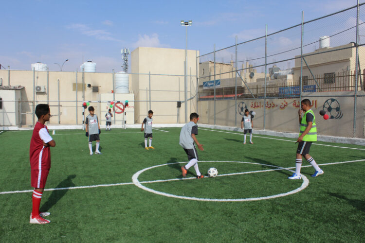 Children play soccer at the new field in Hittin Camp.
