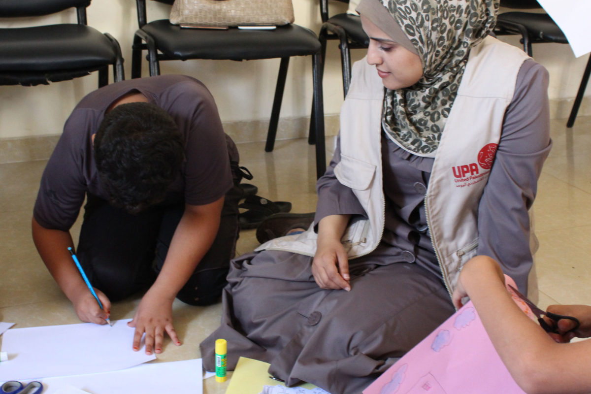 Islam sits with kids during an art session.