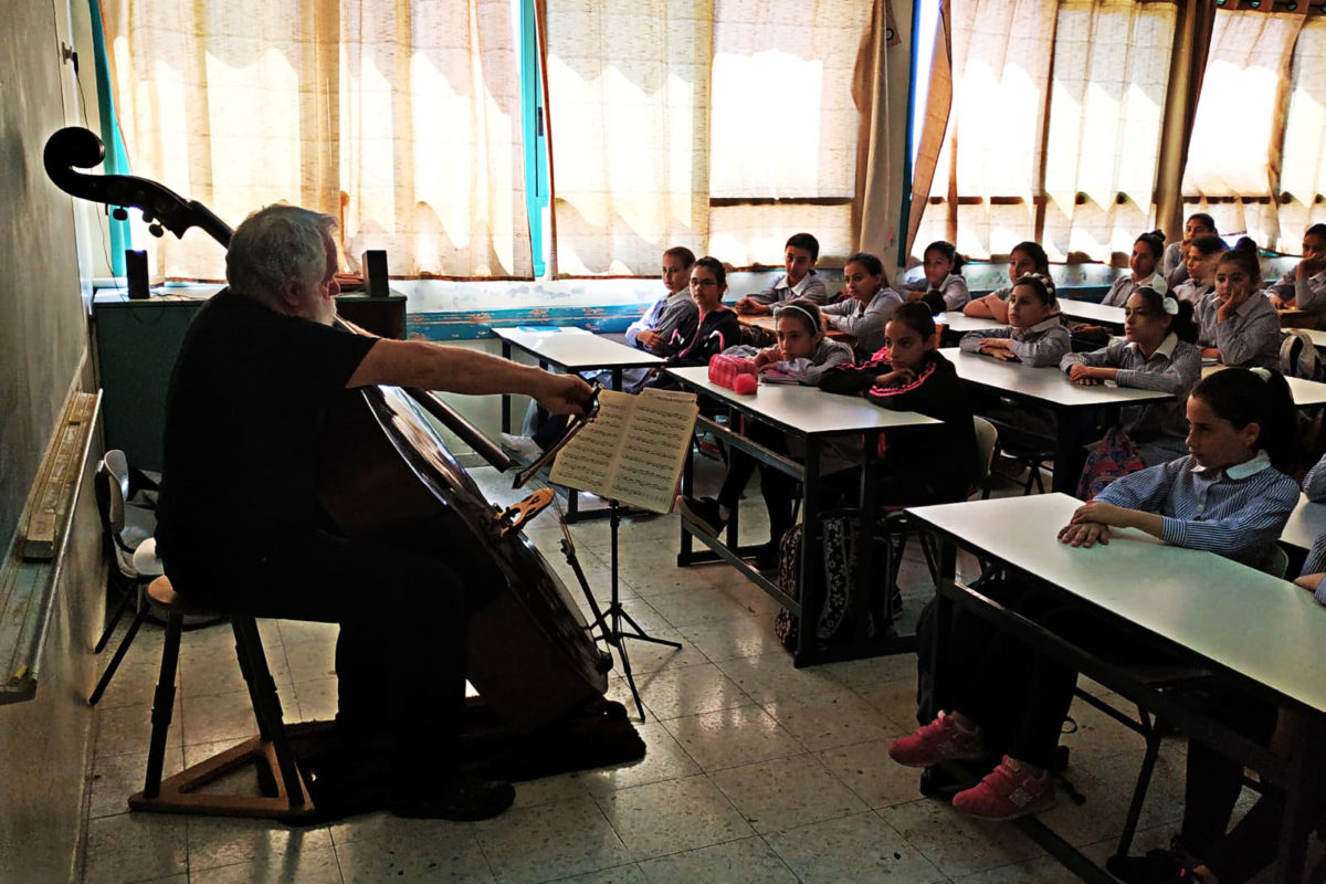 Children watch their teacher on cello.