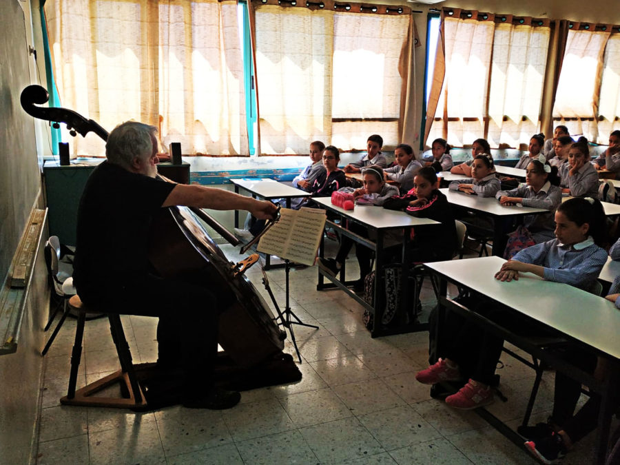 Children watch their teacher on cello.