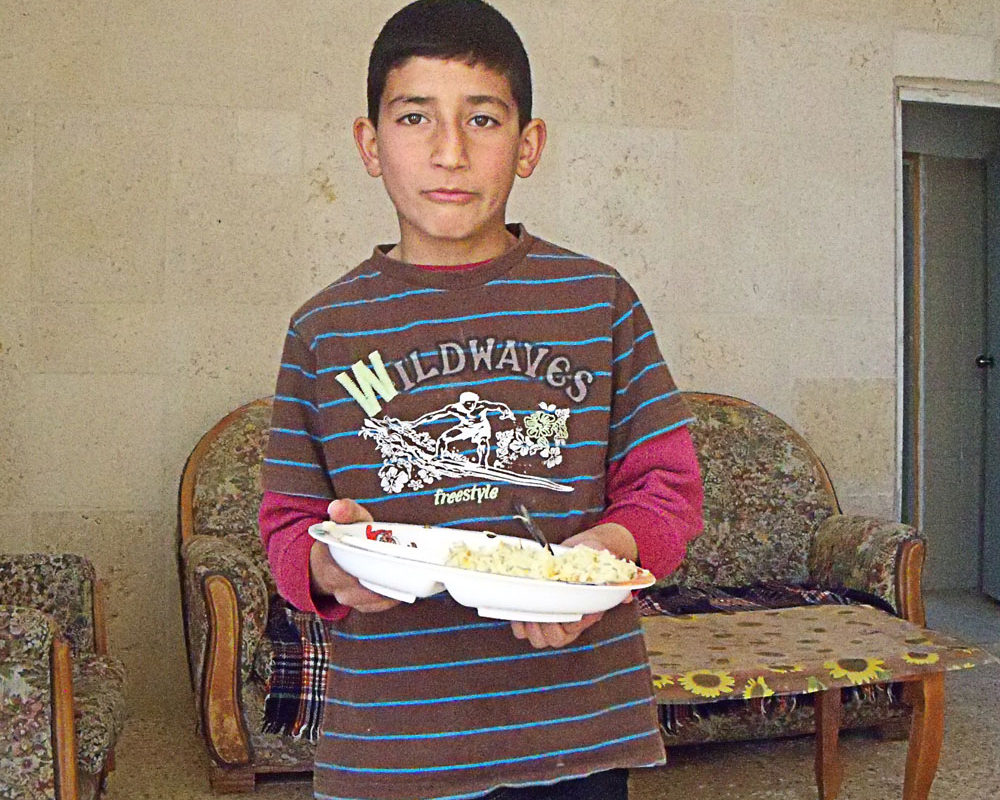 A child holds a plate of food in the West Bank.