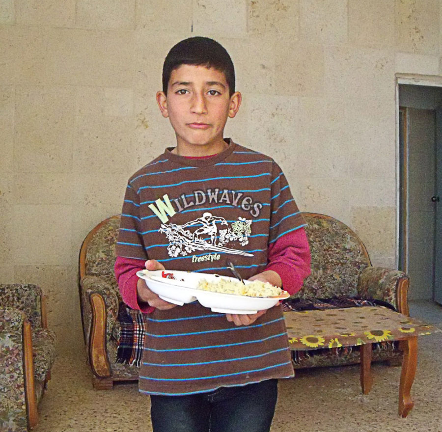 A child holds a plate of food in the West Bank.